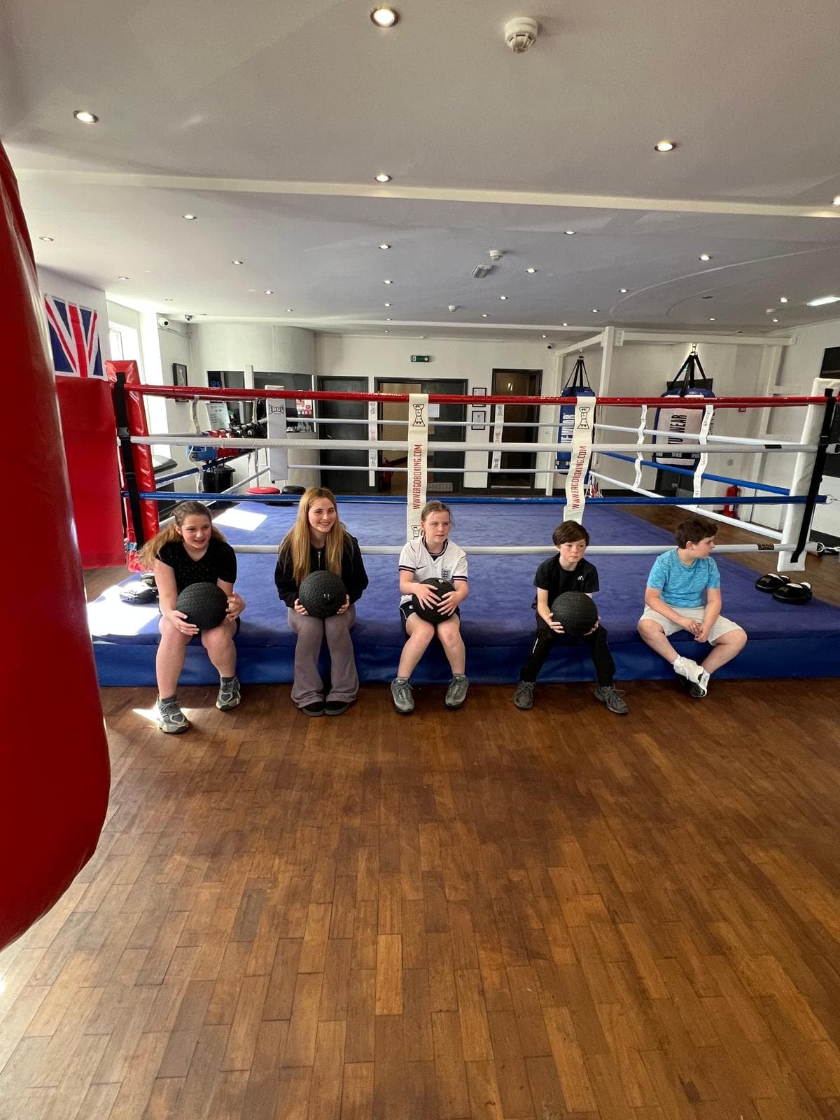 Children sitting beside the boxing ring after a fitness activity